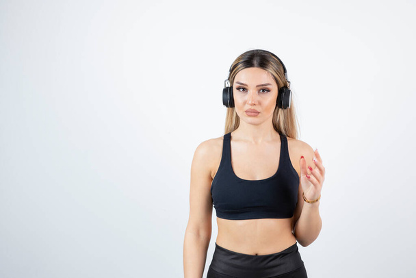 Blonde fit woman in black top listening to songs on headphones. High quality photo - Фото, изображение