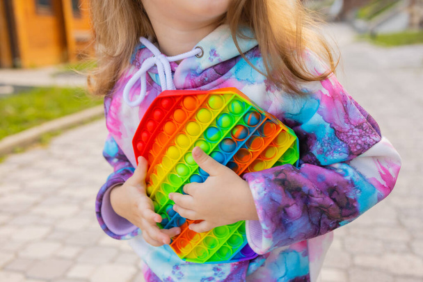 Pop it fidget toy in girl hands. Colorful antistress kids toy fidget. - Foto, Imagem