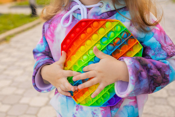 Pop it fidget toy in girl hands. Colorful antistress kids toy fidget. - Valokuva, kuva
