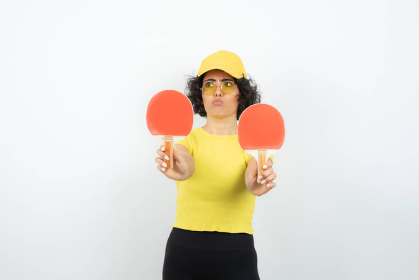 Retrato de estúdio de menina com cabelo encaracolado segurando raquetes de tênis de mesa. Foto de alta qualidade - Foto, Imagem