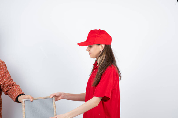 Imagem de uma jovem adolescente de uniforme vermelho tirando da moldura do homem. Foto de alta qualidade - Foto, Imagem