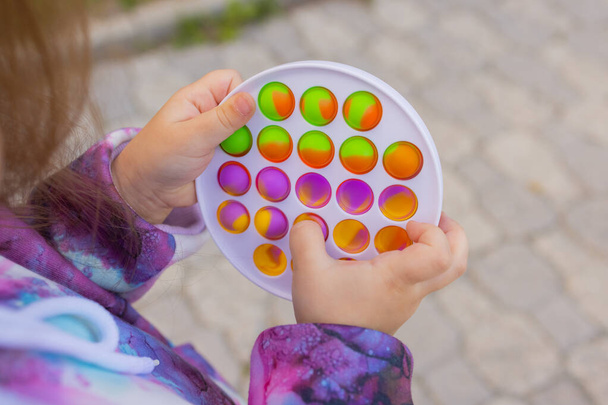 Pop it fidget toy in girl hands. Colorful antistress kids toy fidget. - Foto, afbeelding