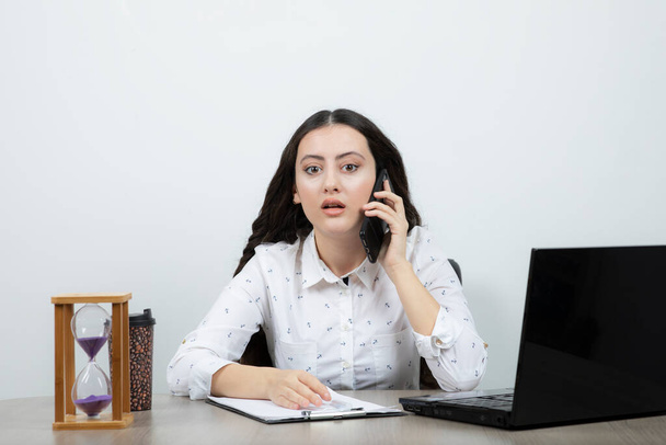 Geschäftsfrau sitzt am Tisch und telefoniert. Hochwertiges Foto - Foto, Bild