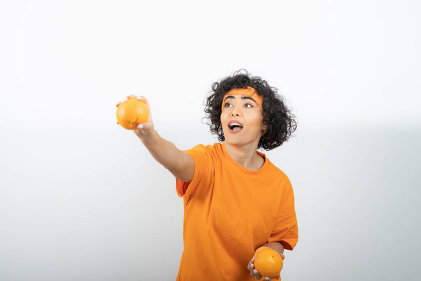 young woman with oranges posing on white background - Photo, Image