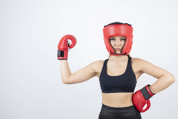 Wizerunek młodej bokserki w czerwonych rękawiczkach i stojącym hełmie. Wysokiej jakości zdjęcie - Zdjęcie, obraz