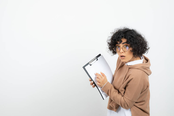 Göndör hajú, szemüveges fiatal nő, üres írótáblával a kezében. Kiváló minőségű fénykép - Fotó, kép