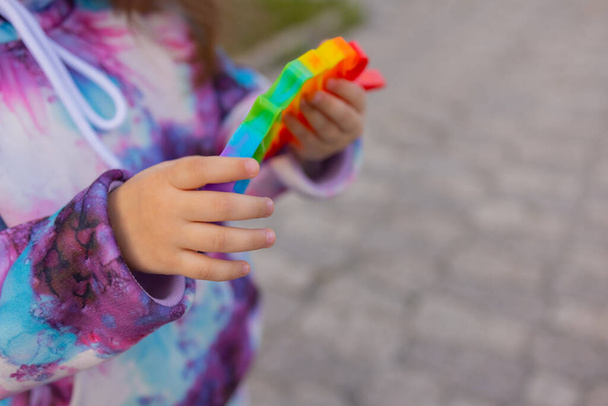 Pop it fidget toy in girl hands. Colorful antistress kids toy fidget. - Foto, afbeelding