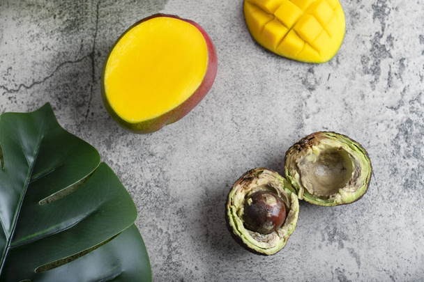Enfes dilimlenmiş avokado ve taş zeminde taze mango. Yüksek kalite fotoğraf - Fotoğraf, Görsel