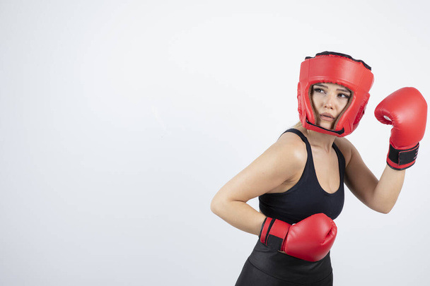 Retrato de jovem boxeador em luvas vermelhas e treinamento capacete. Foto de alta qualidade - Foto, Imagem