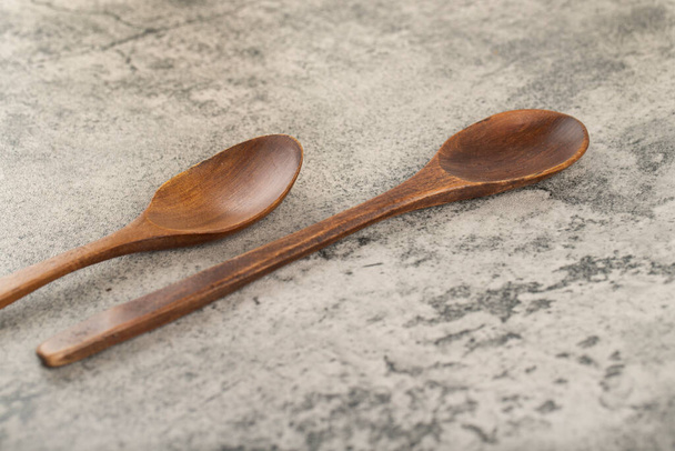 Dos cucharas de madera vacías colocadas sobre fondo de piedra. Foto de alta calidad - Foto, imagen