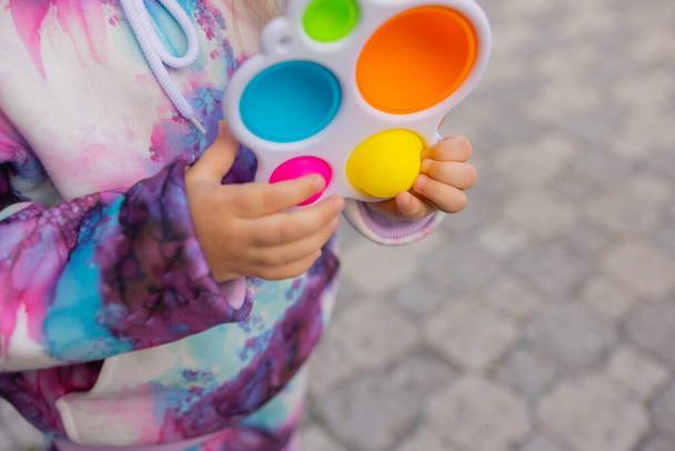 Pop it fidget toy in girl hands. Colorful antistress kids toy fidget. - Zdjęcie, obraz