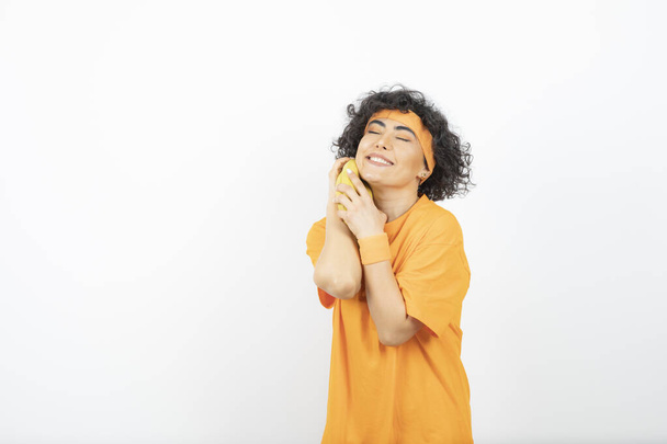 Imagen de una hermosa mujer deportiva en traje naranja abrazando plátanos. Foto de alta calidad - Foto, Imagen