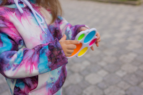 Pop it fidget toy in girl hands. Colorful antistress kids toy fidget. - Fotó, kép