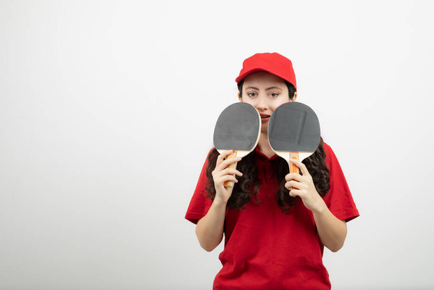 Brunette femme en uniforme rouge tenant des raquettes de tennis de table. Photo de haute qualité - Photo, image