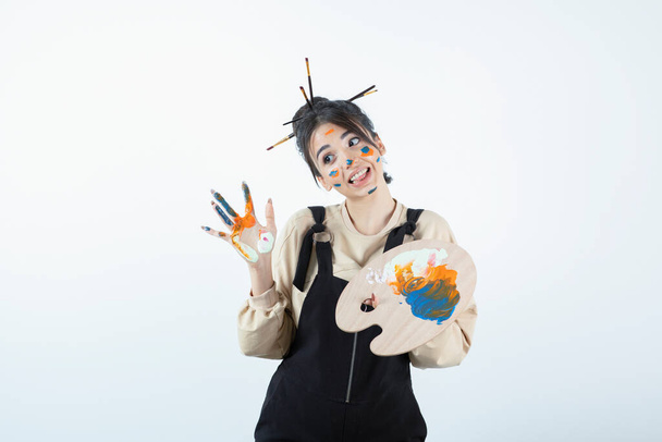 Retrato de una joven artista posando con una cara pintada y sosteniendo una paleta de madera. Foto de alta calidad - Foto, Imagen