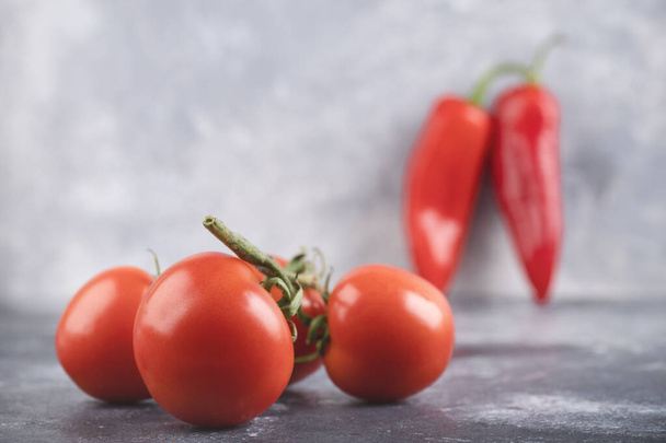 Organická červená rajčata a chilli paprika na mramorovém povrchu. Kvalitní fotografie - Fotografie, Obrázek