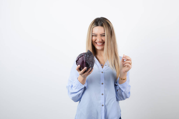 Pretty woman in blue outfit looking at purple cabbage on white background. High quality photo - Fotó, kép