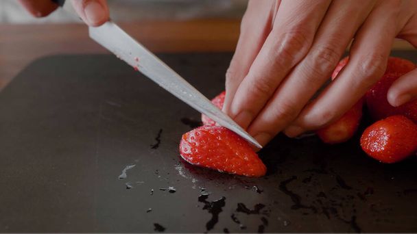 We snijden de stukjes aardbeien op het bord. - Foto, afbeelding