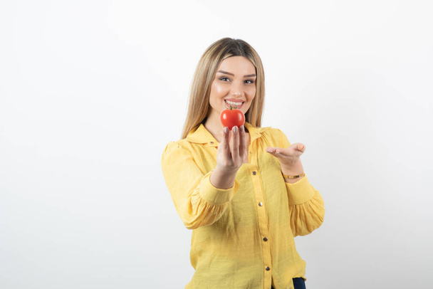 Femme souriante tenant la tomate rouge sur fond blanc. Photo de haute qualité - Photo, image