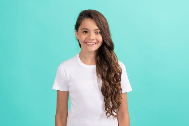 cheerful child long curly hair in white casual shirt on blue background, haircare - Photo, Image