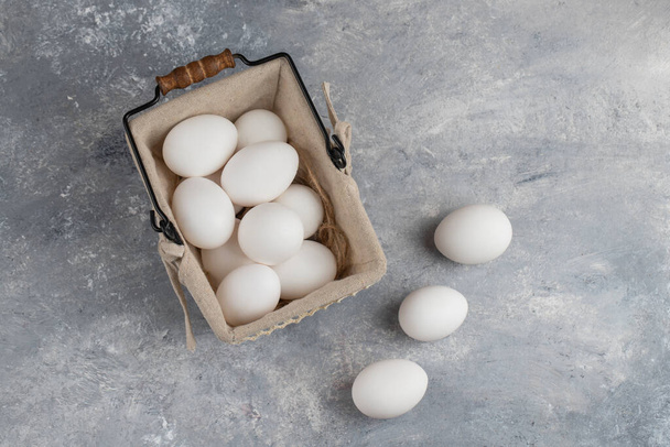 Basket full of fresh white chicken eggs on a marble background . High quality photo - Фото, зображення