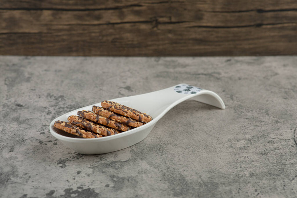 Malý talíř kulatých sušenek se sezamovými semínky na mramorovém podkladu. Kvalitní fotografie - Fotografie, Obrázek