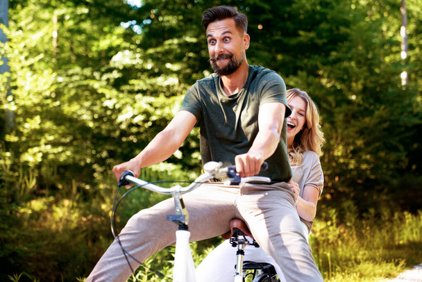 Szczęśliwa para bawiąca się na rowerze w lesie - Zdjęcie, obraz