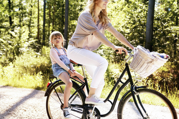 Μητέρα και κόρη κάνουν ποδήλατο στο δάσος. - Φωτογραφία, εικόνα