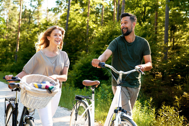 Para pchająca rower w słoneczny dzień                                - Zdjęcie, obraz