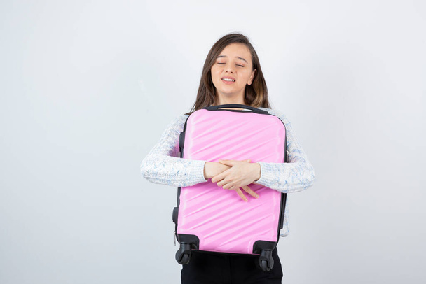 Obrázek mladého turisty drží růžový kufr. Kvalitní fotografie - Fotografie, Obrázek
