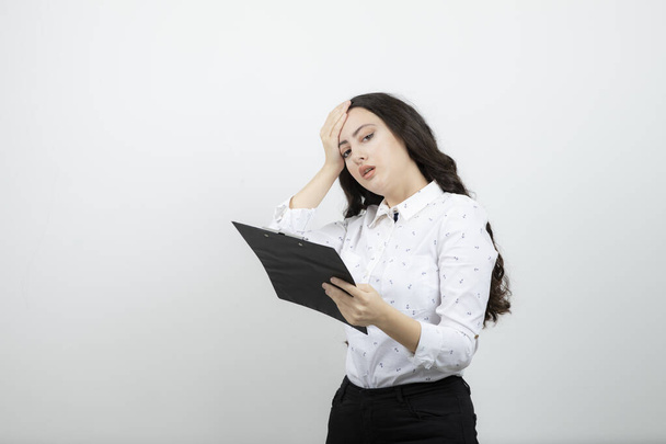 Successful business woman holding clipboard against white wall . High quality photo - Photo, Image