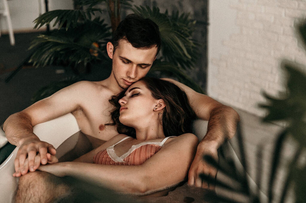 photo of young people in love taking a bath. mental rest. sexual instinct.carnal infatuation. handsome guy is feeling drawn toward his beautiful girlfriend. lovers joy in bathroom. noise, grainy effect - Foto, Imagem