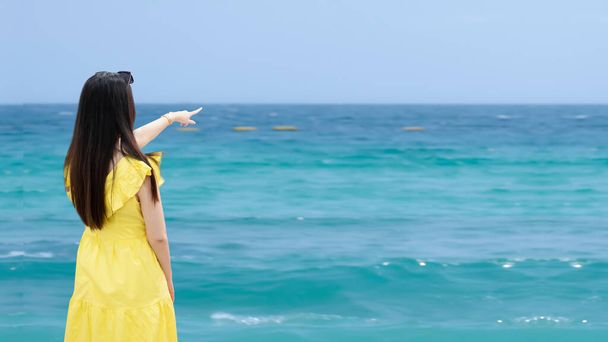 Mujer viajera feliz en vestido amarillo disfruta en la playa tropical. Retrato hermosa asiática joven feliz momento en verano. Chica sexy relajarse en verano de vacaciones. - Foto, imagen
