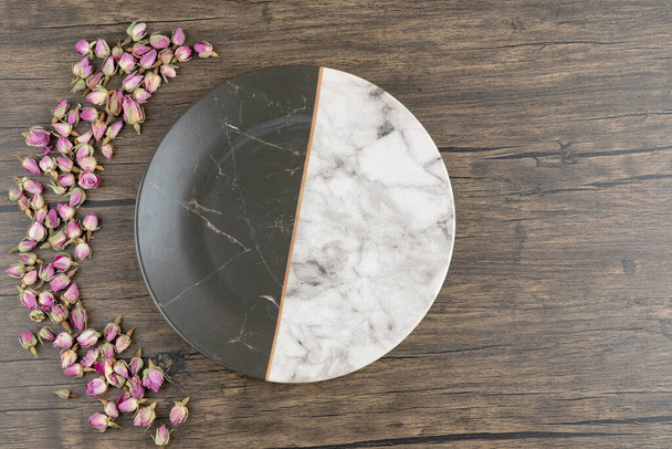 A plate with dried rose flowers on a wooden background . High quality photo - 写真・画像