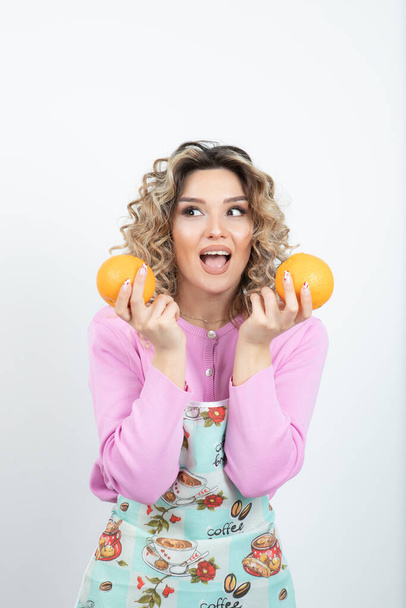 Photo of beautiful housewife with fresh oranges posing over white. High quality photo - Fotoğraf, Görsel