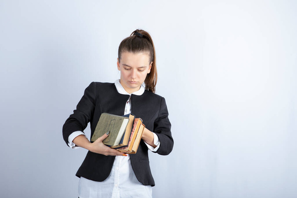 Retrato de una joven sosteniendo libros sobre fondo blanco. Foto de alta calidad - Foto, Imagen