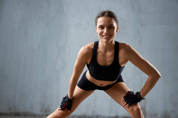 Smiling fit woman practicing legs stretching. - Photo, image