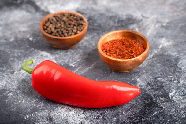 Rode chili peper met gemalen peper vlokken en peperkorrels op marmer. Hoge kwaliteit foto - Foto, afbeelding