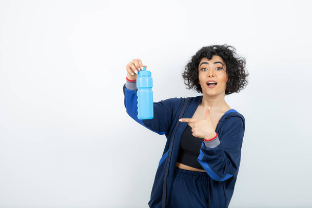 Bella vestibilità sportiva donna in possesso di bottiglia d'acqua blu. Foto di alta qualità - Foto, immagini