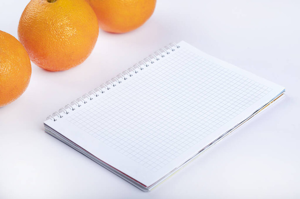 Exotic juicy orange fruits and empty notebook on white background. High quality photo - Фото, изображение