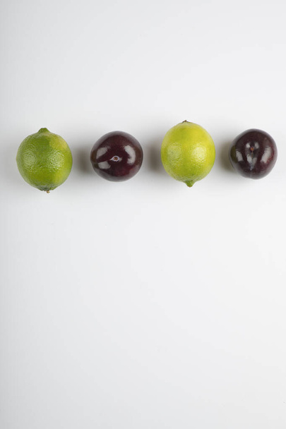 Δύο φρούτα λάιμ και φρέσκα δαμάσκηνα σε λευκό φόντο. Υψηλής ποιότητας φωτογραφία - Φωτογραφία, εικόνα