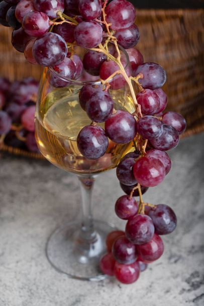 Glass of white wine with fresh red grapes on stone background. High quality photo - Φωτογραφία, εικόνα