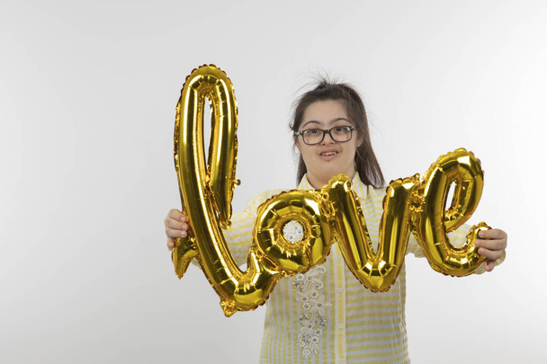 Portrait of young girl with a Down syndrome holding air balloon . High quality photo - 写真・画像