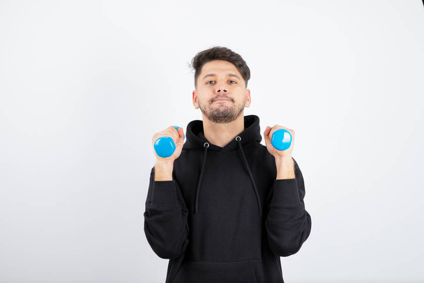 Imagen de un joven en forma entrenando con pesas azules. Foto de alta calidad - Foto, imagen