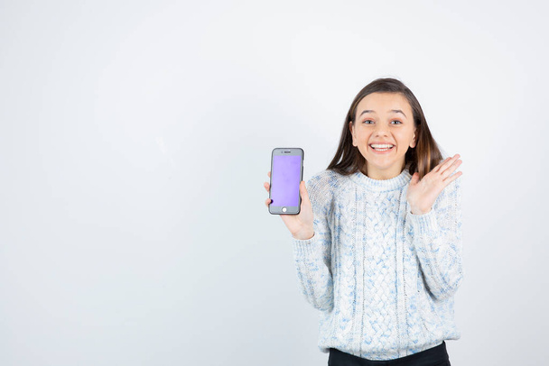 Jong tienermeisje met smartphone op witte achtergrond. Hoge kwaliteit foto - Foto, afbeelding