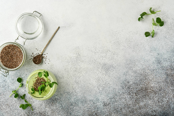 Ingredients for green smoothie, fresh organic spinach pea microgreens, banana, kiwi, apple and chia seed over light grey concrete background. Healthy eating ingredients. Top view, copy space - Foto, imagen