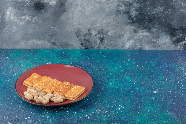 A red plate with healthy nuts and delicious crackers on galaxy background. High quality photo - Fotó, kép