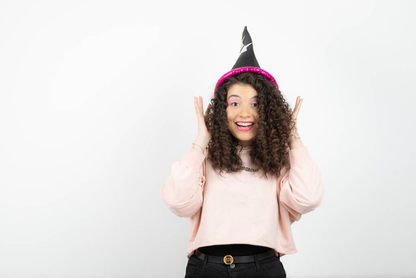 Adorable young woman with curly hair wearing special hat for party. High quality photo - Фото, изображение