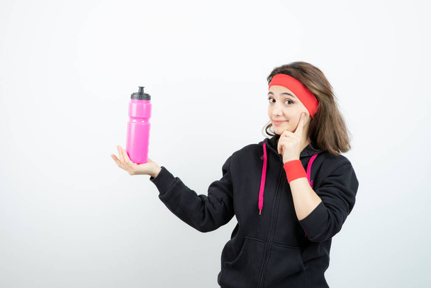 Beautiful sporty woman holding bottle with water on white wall . High quality photo - Φωτογραφία, εικόνα