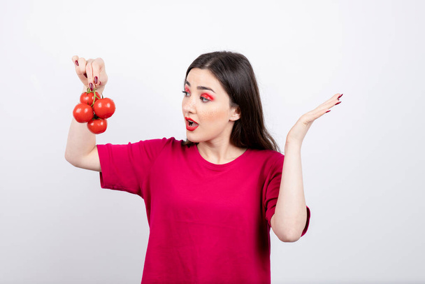 Kaunis brunette nainen katselee tuoreita punaisia tomaatteja. Laadukas kuva - Valokuva, kuva
